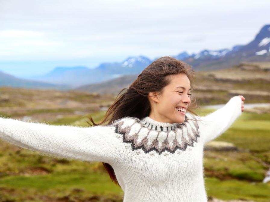 kvinde med hjemmestrikket trøje og bjerge i baggrunden